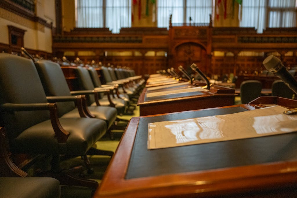 A detailed view of an empty legislative chamber with rows of desks and microphones, evoking governance.